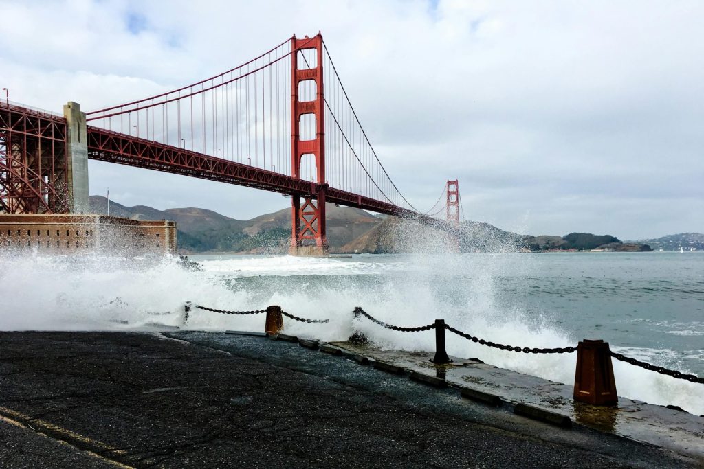 Dramatic waves crashing at the iconic Golden Gate Bridge in San Francisco, showcasing its architectural beauty.