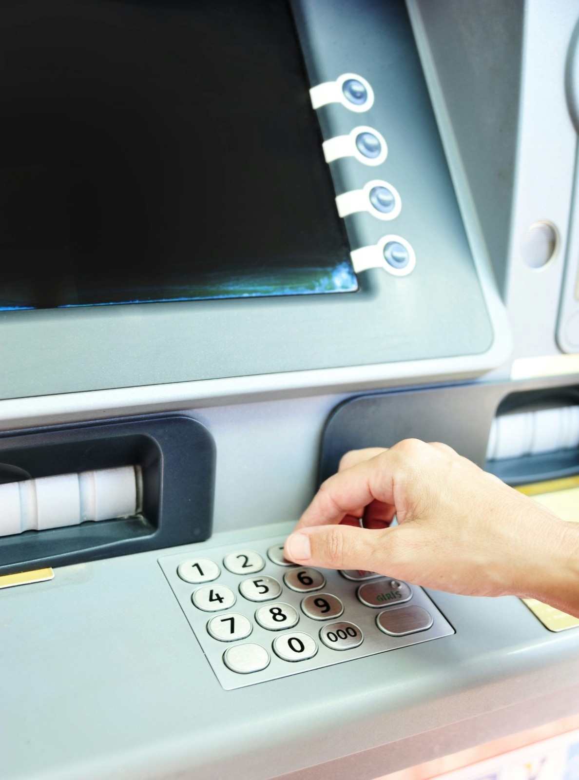Hand using keypad on an atm machine.
